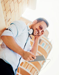 Portrait of handsome young smiling man with tablet. Listening to