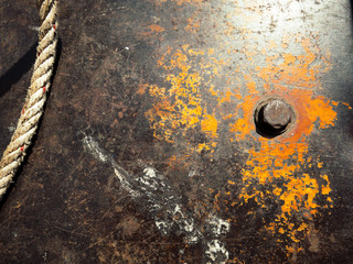 Rusty metal plat with rope and bolt.