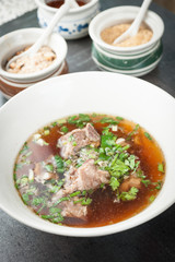 Asian style pork bone soup with seasoning on dark stone background