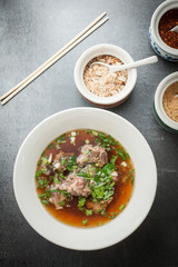 Asian style pork bone soup with seasoning on dark stone background