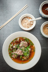 Asian style pork bone soup with seasoning on dark stone background