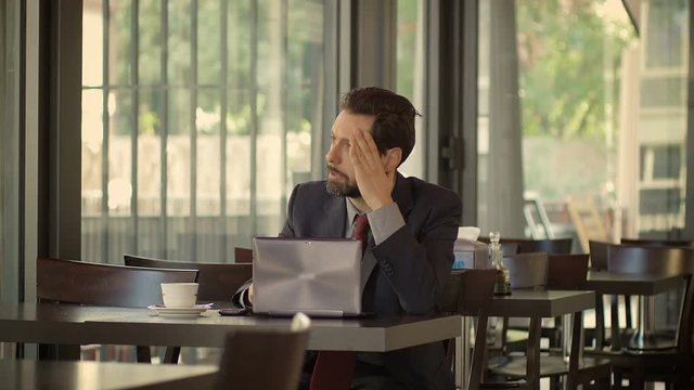 troubled and desperate businessman sitting and working in a cafè: cafeteria