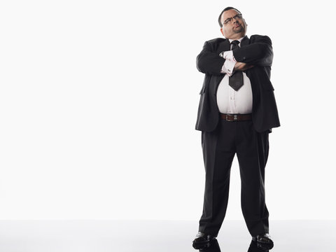 Full length of an overweight businessman standing with arms crossed against white background