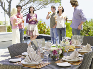 Fine dining table setting with friends enjoying drinks in background
