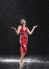 Naklejka na ściany i meble Full length of a young cheerful woman with arms out standing in rain