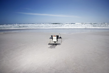 Rear view of a senior businessman relaxing at office desk on beach