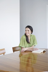Naklejka premium Beautiful young woman with book at dining table smiling