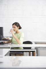 Young businesswoman drinking water at computer desk in office