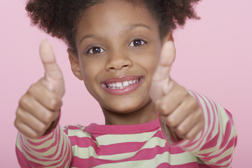 Closeup portrait of a happy girl giving double thumbs up on pink background