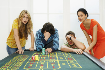 Group of multiethnic friends losing on roulette table