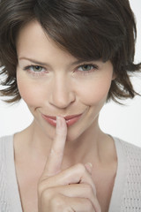 Naklejka premium Closeup of a mischievous woman with finger on lips