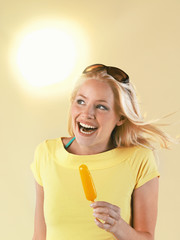 Portrait of a beautiful young woman holding popsicle on a hot summer day