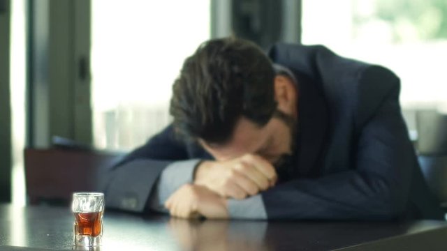 desperate businessman sitting alone in a cafeteria: alcohol, depression, sadness