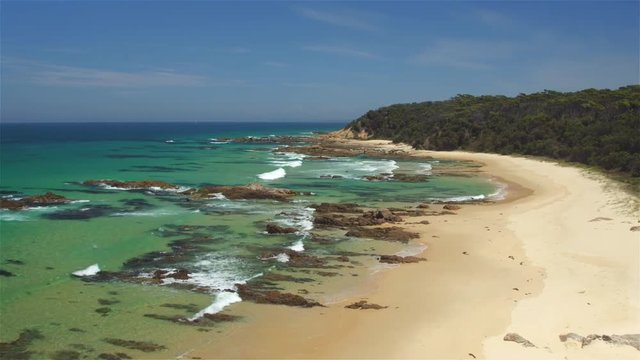 AERIAL: Flying above pretty diversified ocean shore, green sea and sandy beach 