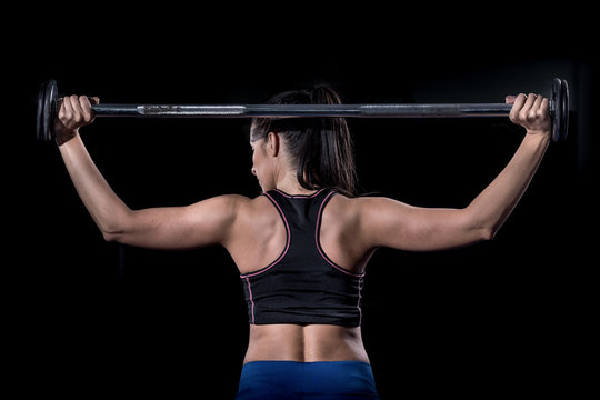 Woman bodybuilder  lifting barbell isolated over black background