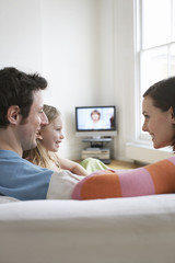 Parents with daughter relaxing on sofa in living room