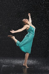Fototapeta na wymiar Full length of a young cheerful woman with arms out dancing in rain