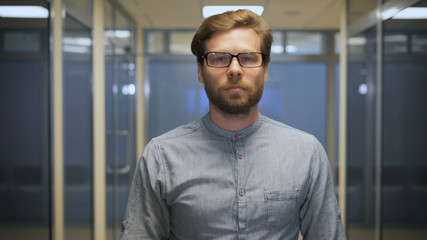 Young bearded businessman rearranges glasses