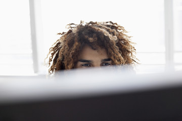Closeup of a young man with curly hair using computer in the office