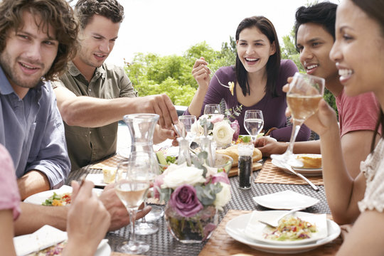 Group of multiethnic friends enjoying dinner party outdoors