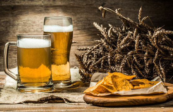 Beer in mug, glass with wheat spikelets and chips