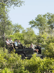 Side view of four tourists and driver in jeep on safari 