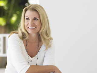 Smiling middle aged woman sitting on verandah and looking away