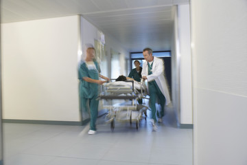 Medical workers moving patient on gurney through hospital corridor