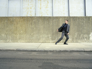 Full length of businessman in suit running on pavement looking back