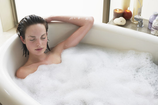 Elevated view of beautiful young woman relaxing with eyes closed in bathtub