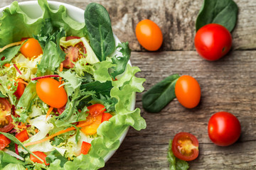 Salad with fresh vegetables - tomatoes, carrots, bell peppers and mixed greens - arugula, mesclun, mache.