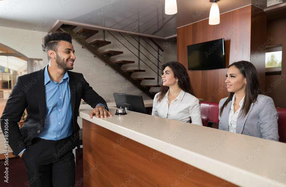 Wall mural Young Business Man On Hotel Reception Office, Businessman Check In Formal Trip Arrive Woman At Front Desk Meeting Stuff