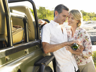 Happy adult couple by jeep with man pouring wine in glass © MDBPIXS