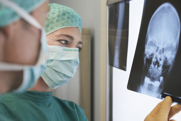 Closeup of two radiologists examining xray of skull