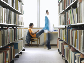 Side view of a young male college student doing homework in the library