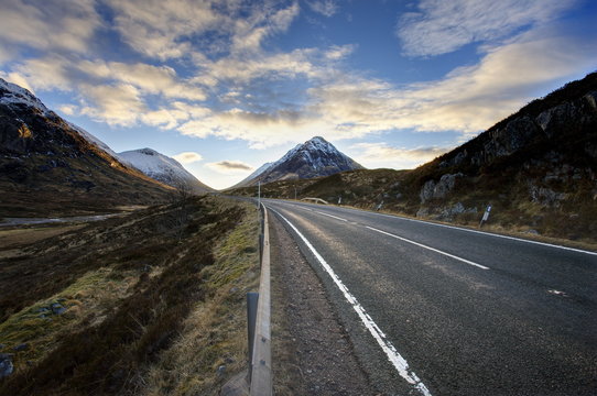 A82 trunk road heading across Rannoch Moor towards Glencoe with snow-covered mountains in distance and dramatic evening sky, Rannoch Moor, near Fort William, Highland, Scotland