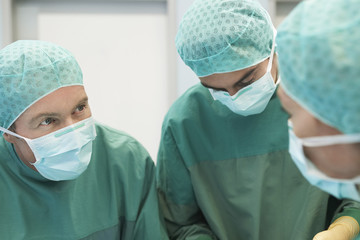 Closeup of three surgeons at work in the operating theatre