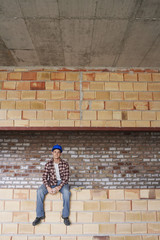 Fototapeta na wymiar Portrait of a male construction worker sitting on brick wall