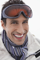 Closeup portrait of a young smiling man wearing ski goggles