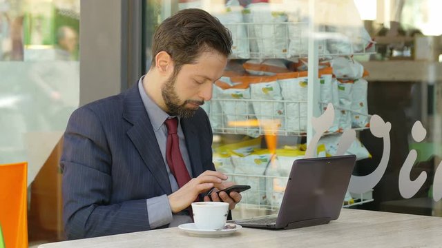 businessman at work with laptop and smartphone and drinking coffee
