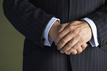 Closeup midsection of a businessman in suit standing with hands clasped