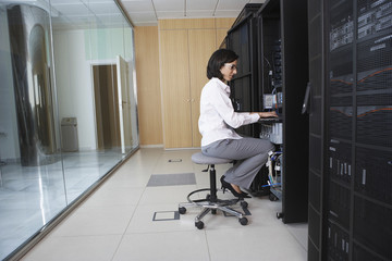 Full length side view of female technician working in server room