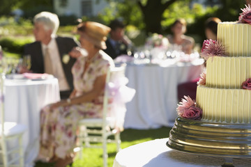 Closeup of wedding cake with guests sitting at tables in background