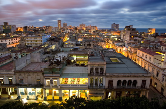 View over Havana Centro at night from 7th floor of Hotel Seville showing contrast of old, semi-derelict apartment buildings against a backdrop of more modern, affluent architecture, Havana, Cuba