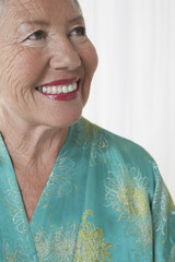 Closeup of a cheerful senior woman looking up against white background