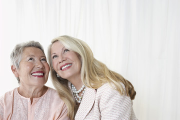 Two happy elegant senior women looking up against white background