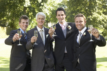 Portrait of happy four men toasting champagne flutes at wedding day