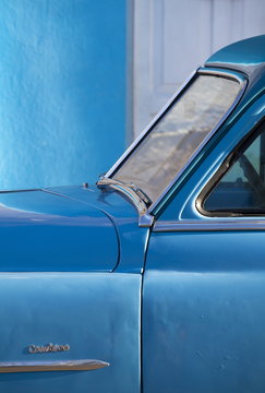 Detail of vintage blue American car against painted blue wall, Cienfuegos, Cuba 