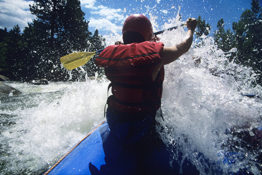 Rear view of a male kayaker paddling through rapids