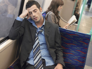 Businessman with loosened tie sleeping in commuter train
